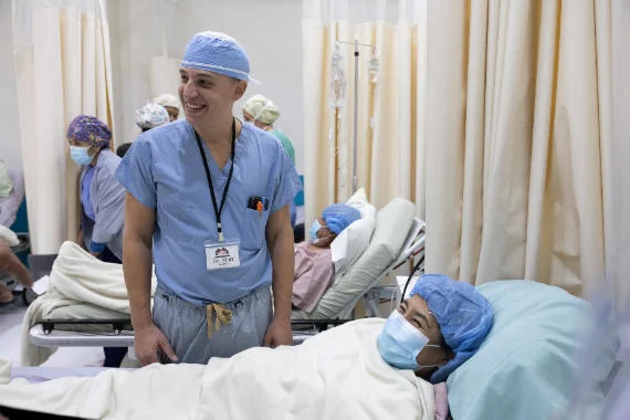 Dr. Grosso in scrubs at a patient’s bedside on the ward.