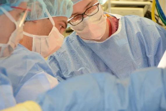 Surgeons in masks and loupes concentrating during an operation.